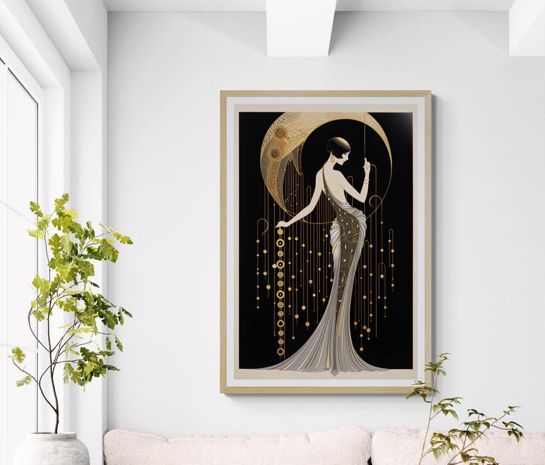 May include: A framed wall art print featuring a stylised figure in a long, flowing gown standing before a large golden crescent moon. The design incorporates black, gold, and cream tones with intricate geometric patterns and hanging circular accents.