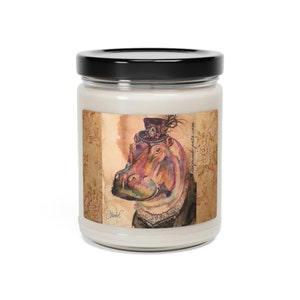 Puede incluir: Un tarro de vela blanco con tapa negra y una etiqueta con una ilustración de acuarela de un hipopótamo con un sombrero de copa y una boa de plumas. La etiqueta también incluye el texto "Habibi" y "etsy.com/shop/houseofpeta".