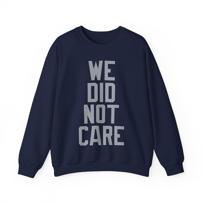 May include: Navy blue sweatshirt with the text "WE DID NOT CARE" in gray block letters. The crew neck sweatshirt has long sleeves and a relaxed fit. The text is centered on the front of the garment.