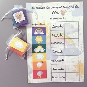 Può includere: Un grafico colorato con un design a arcobaleno e il testo "La météo du comportement de Léa La semaine du" con i giorni della settimana elencati: Lundi, Mardi, Mercredi, Jeudi, Vendredi, Samedi, Dimanche. Ogni giorno ha un cerchio per un adesivo.