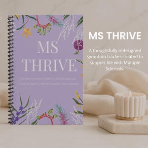 May include: A lavender spiral-bound notebook titled "MS THRIVE" with floral illustrations. The text reads, "A Simple Symptom Tracker for Multiple Sclerosis." A candle and vase with dried flowers are in the background.