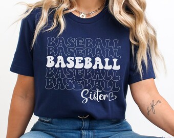 May include: Navy blue t-shirt with the word "BASEBALL" stacked multiple times in a retro font. The word "Sister" is below the word "BASEBALL". The shirt is made of a soft material.