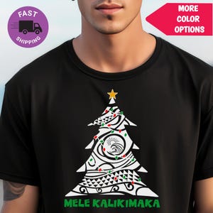 Peut inclure: T-shirt noir avec un motif d'arbre de Noël blanc, une étoile dorée, des lumières rouges et vertes et des motifs tribaux. L'expression "MELE KALIKIMAKA" est imprimée en vert. Le t-shirt a un col rond.