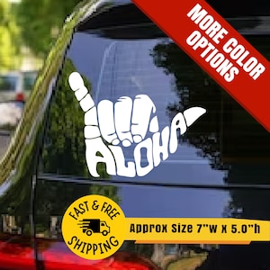 May include: White vinyl decal featuring the shaka hand gesture with the word "ALOHA" in a stylized font. The decal is approximately 7 inches wide and 5 inches high. A red banner reads "MORE COLOR OPTIONS". A yellow circle reads "FAST & FREE SHIPPING".