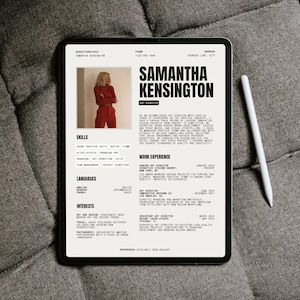 Puede incluir: Una tableta digital que muestra un currículum vitae de Samantha Kensington, Directora de Arte. El currículum incluye habilidades, experiencia laboral, idiomas e intereses. Un lápiz óptico blanco descansa junto a la tableta, sobre un fondo gris texturizado.