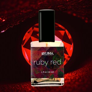 May include: A perfume bottle with a black cap and a label that reads "ruby red." The bottle is 1 fl oz (30 ml). The background features a large red gemstone and a dark red gradient.