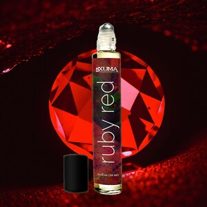 May include: A roll-on perfume bottle with the text "ruby red" and "EXUMA Fragrance Co." against a red background. The bottle is .33 fl oz (10 ml) and has a black cap.