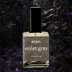 Puede incluir: Botella de perfume rectangular con tap&oacute;n negro. La etiqueta dice "EXUMA FRAGRANCE CO." y "violet gray". La botella contiene 30 ml de perfume. El fondo es una imagen oscura y borrosa de follaje.