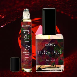 May include: Two perfume bottles with the text "ruby red" are displayed against a dark red background. One is a roll-on bottle, the other is a square bottle with a black cap. The roll-on bottle is labeled as .33 fl oz (10 ml), and the square bottle is labeled as 1 fl oz (30 ml).