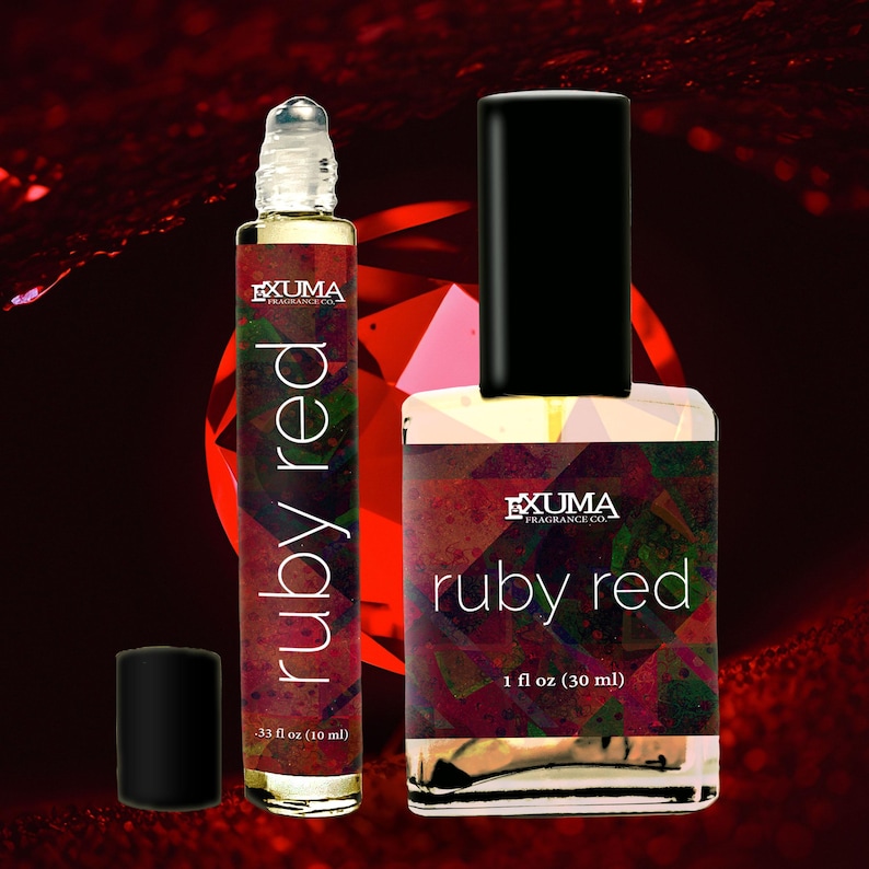 May include: Two perfume bottles with the text "ruby red" are displayed against a dark red background. One is a roll-on bottle, the other is a square bottle with a black cap. The roll-on bottle is labeled as .33 fl oz (10 ml), and the square bottle is labeled as 1 fl oz (30 ml).