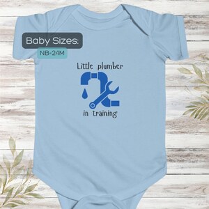 May include: Pale blue baby bodysuit featuring the text "Little plumber in training" in dark blue. The design includes a wrench and a pipe with a water droplet. Available in sizes NB-24M.