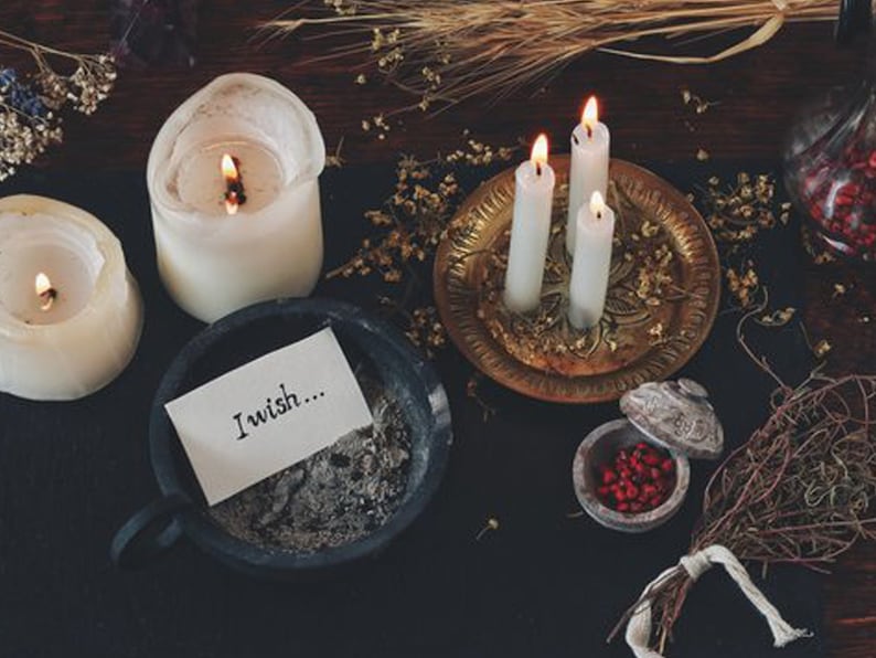 May include: A dark wooden surface with three white candles, a small bowl of red berries, a note that says "I wish..." and a small brass tray with a decorative design.