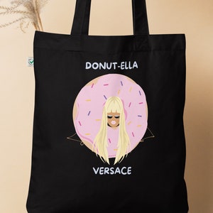 May include: Black tote bag with a pink and white donut with a woman's face inside. The text "DONUT-ELLA VERSACE" is printed on the bag.