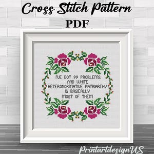 Könnte beinhalten: Ein gerahmtes Kreuzstichmuster mit dem Text "I'VE GOT 99 PROBLEMS AND WHITE HETERONORMATIVE PATRIARCHY IS BASICALLY MOST OF THEM", umgeben von einem floralen Kranz. Die Worte "Cross Stitch Pattern PDF" stehen oben.