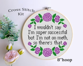 May include: Cross stitch kit featuring a purple floral design with the text "I wouldn't say I'm super successful but I'm not on meth, so there's that." The kit is for an 8 inch hoop.
