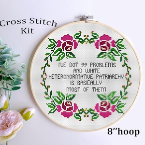 May include: Cross stitch pattern with a white background and pink flowers. The pattern reads "I've got 99 problems and white heteronormative patriarchy is basically most of them". The pattern is designed for an 8 inch hoop.