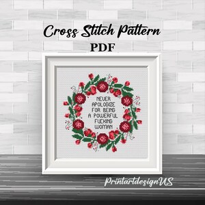 May include: A framed cross-stitch pattern with the text "NEVER APOLOGIZE FOR BEING A POWERFUL FUCKING WOMAN" surrounded by a floral wreath. The words "Cross Stitch Pattern PDF" are at the top. The frame is white.