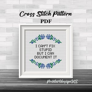 May include: A framed cross-stitch pattern with the text "I CAN'T FIX STUPID BUT I CAN DOCUMENT IT." The design includes blue floral accents and the words "Cross Stitch Pattern PDF." The frame is white, and the background is a brick wall.
