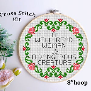 May include: Cross stitch kit featuring a white embroidery hoop with a green and red floral design and the text "A WELL-READ WOMAN IS A DANGEROUS CREATURE". The hoop is 8 inches in diameter.
