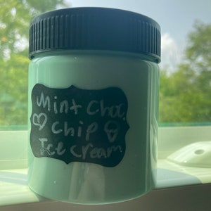 May include: A green glass jar with a black lid and a black and white label that says "Mint cha. chip & Ice cream".