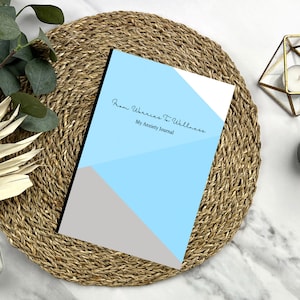 Könnte beinhalten: Ein blaues und graues Journal mit dem Text "From Worries To Wellness My Anxiety Journal" auf dem Cover.