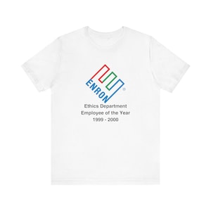 Op de afbeelding: Wit T-shirt met een blauw, groen en rood logo met de tekst "Enron" en de tekst "Ethics Department Employee of the Year 1999 - 2000".