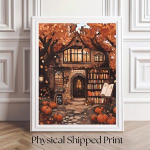 May include: A framed print of a whimsical autumn scene. The artwork depicts a cozy cottage bookstore with pumpkins, trees with orange leaves, and a sign that reads "Pumpkin Spice & Gentle Nights". The text "Physical Shipped Print" is at the bottom.