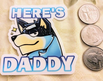 May include: A sticker with the text "HERE'S DADDY" and a cartoon dog illustration in blue, black, and yellow. Three quarters are next to the sticker.