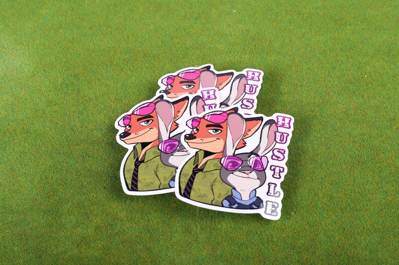 May include: Two stickers featuring cartoon characters from the movie Zootopia. The characters are a fox and a rabbit wearing sunglasses. The stickers have the word "Hustle" written vertically on them.