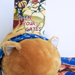 K&ouml;nnte beinhalten: Ein Cartoon-Bild von Bowser, einer Videospielfigur, mit dem Text "OPEN YOUR GATES" auf dem Bild. Das Bild ist auf einer Karte gedruckt.