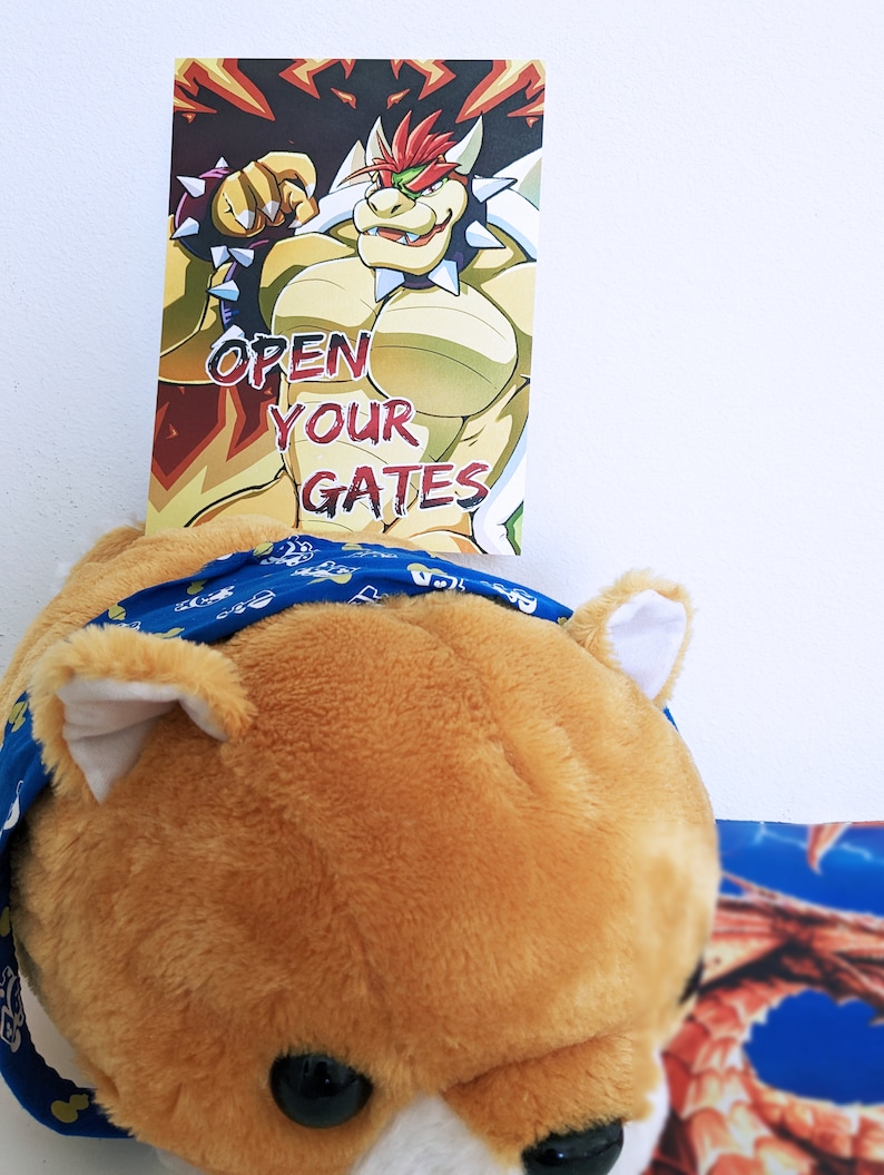K&ouml;nnte beinhalten: Ein Cartoon-Bild von Bowser, einer Videospielfigur, mit dem Text "OPEN YOUR GATES" auf dem Bild. Das Bild ist auf einer Karte gedruckt.