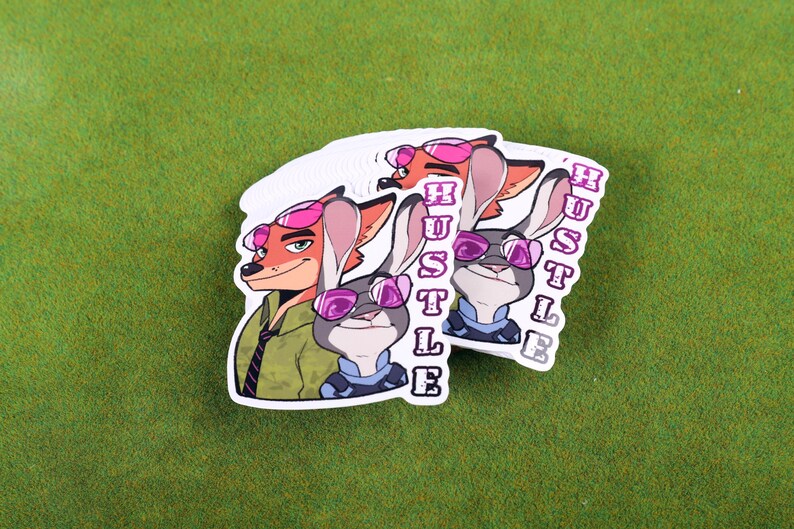 May include: Two stickers featuring cartoon characters from the movie Zootopia. The characters are a fox and a rabbit wearing pink sunglasses. The word "Hustle" is written vertically on each sticker.