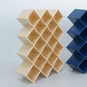 Puede incluir: Dos estanterías de almacenamiento decorativas con un patrón de diamante. La estantería de la izquierda es beige y la estantería de la derecha es azul.