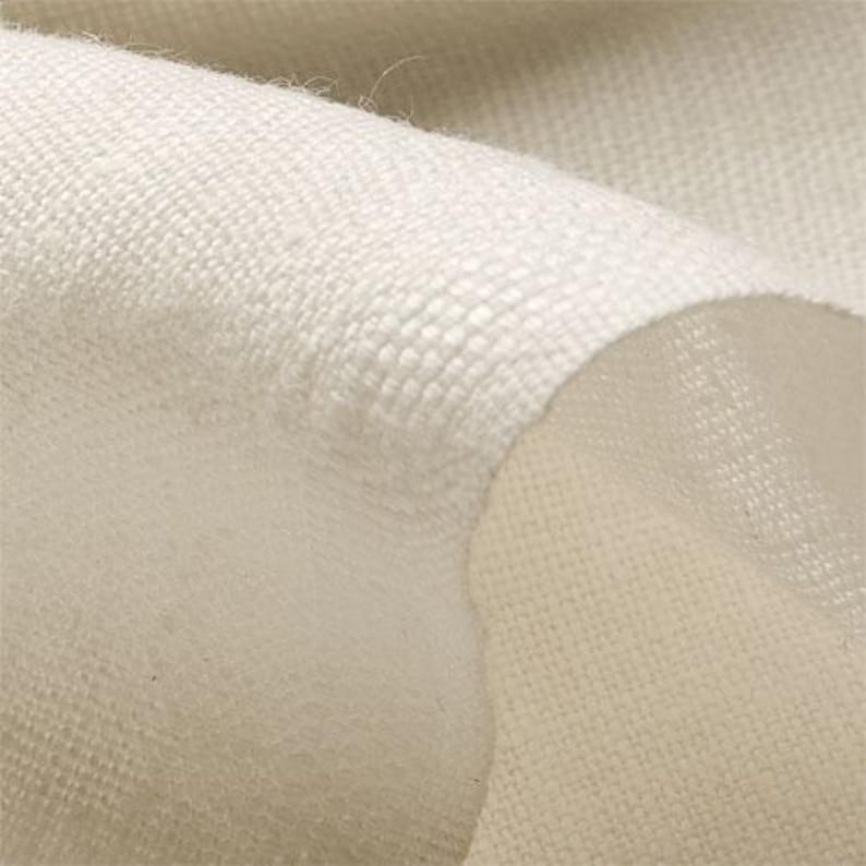 May include: Close-up of off-white fabric with a woven texture. The fabric is folded, revealing a layered effect and a soft, slightly fuzzy underside. The weave appears tight and durable, suggesting a textile suitable for various applications.