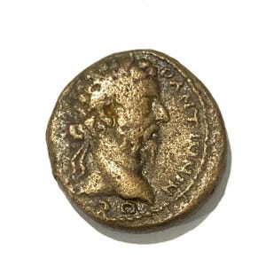 May include: A bronze Roman coin with a portrait of a man on one side and Latin text on the other.