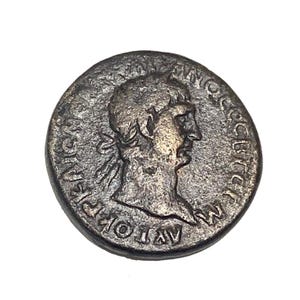 Puede incluir: Una moneda romana de bronce con el perfil de un hombre en un lado y texto alrededor del borde. El texto dice "IMP CAESAR AVG F."