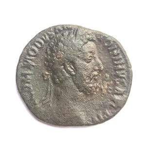 Puede incluir: Una moneda romana de bronce con la inscripción "IMP CAES DOMITIANVS AVG GERM" y un retrato de un hombre con una corona de laurel.