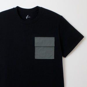 May include: A black short-sleeved t-shirt with a large, dark green utility pocket on the left side.