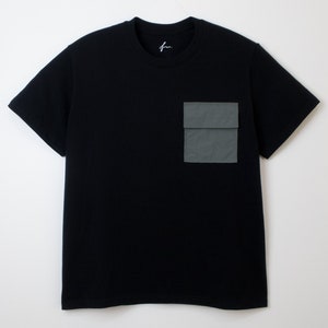 May include: A black t-shirt with a large, dark green utility pocket on the left side.