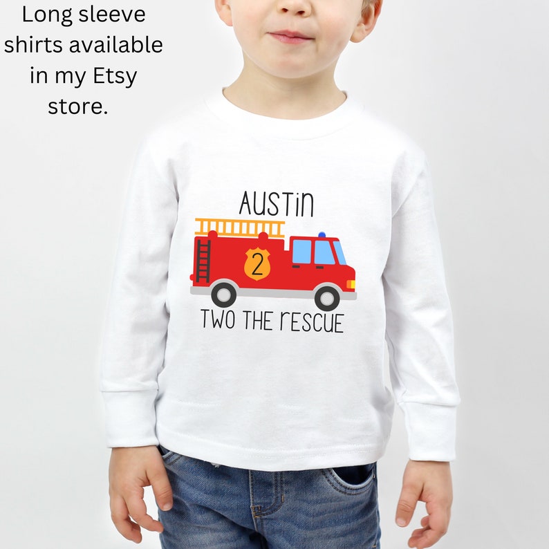 Puede incluir: Una camiseta blanca de manga larga con un gr&aacute;fico de un cami&oacute;n de bomberos rojo con una escalera amarilla, una insignia amarilla con el n&uacute;mero 2 y el texto AUSTIN y TWO THE RESCUE. El texto Long sleeve shirts available in my Etsy store aparece arriba.