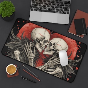 Könnte beinhalten: Schwarzes rechteckiges Mauspad mit einem Skelettpaar, das sich vor einem roten Mond mit Herzakzenten umarmt. Das Design umfasst schwarze, federartige Elemente und eine weiße Maus. Ein Laptop, ein Notizbuch und eine Kaffeetasse sind ebenfalls sichtbar.