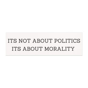 May include: A rectangular white sign with black text that reads "ITS NOT ABOUT POLITICS ITS ABOUT MORALITY". The text is centered and in a sans-serif font.