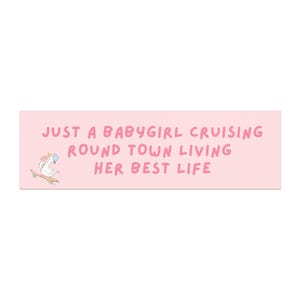 May include: A light pink rectangular sticker with the text "JUST A BABYGIRL CRUISING ROUND TOWN LIVING HER BEST LIFE" in pink. A cartoon duck wearing a bow and a blue bonnet is riding a skateboard.