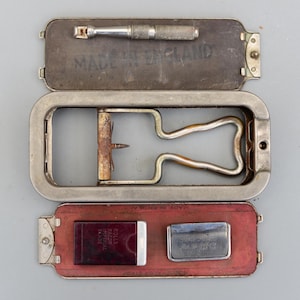 Può includere: Un kit aperto vintage Rolls Razor Imperial Blade. Il kit include un telaio per rasoio in metallo, un cuoio per affilare, una lama e un piccolo utensile in metallo. La custodia è contrassegnata con "MADE IN ENGLAND".
