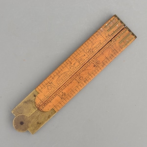 May include: A folding wooden ruler with brass hinges and fittings. The light brown wood features black printed markings and numbers, including the text 'Stanley Rule & Level Co' and 'Trade Mark'. The ruler is shown in a partially folded position.