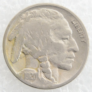 Può includere: Una moneta da cinque centesimi di Buffalo del 1920-S in argento con il profilo di un indiano americano sul dritto. La moneta ha la scritta "LIBERTY" incisa sul lato destro e la data "1920" in basso.