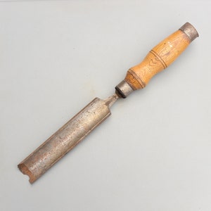 May include: A vintage wood and metal chisel with a wooden handle and a metal blade. The blade is slightly rusted and the handle is worn.