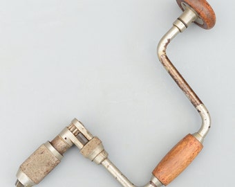 May include: A vintage hand drill with a wooden handle and a metal crank. The drill is silver with some rust and has a wooden handle.