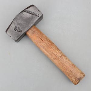 May include: A vintage sledgehammer with a wooden handle and a dark metal head. The head is stamped with the text "BURGON & BALL" and "31 lbs". The handle is made of light brown wood.