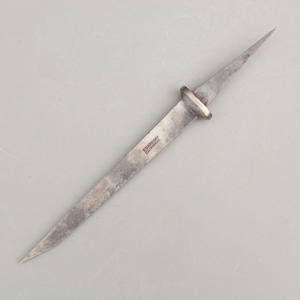 May include: A double-pointed metal awl with a weathered gray finish and a central circular bolster. The tool features the stamped text "BRADBURY" and "CASTSTEEL" on one side of the blade, showcasing a tapered design on both ends.